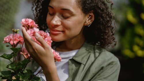 Mulher cheirando flores. A imagem ilustra as emoções e lembranças pelo olfato.